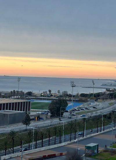 A view across a road and some playing fields to the sea and sun