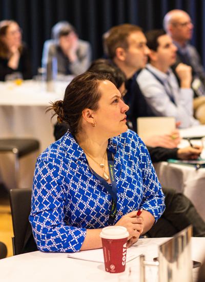 A woman in a blue and white shirt is sitting at a table in the middle of a room 