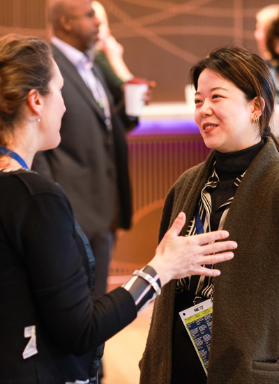 Two women talking with a registration desk in the background