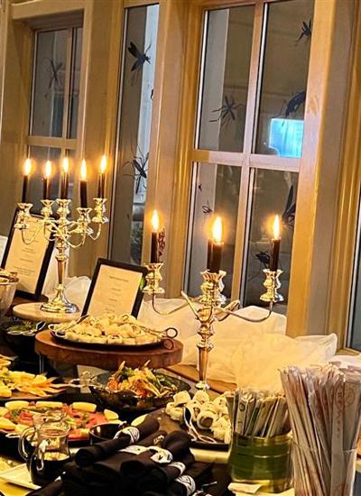 A dining table with a buffet laid out in front of a window decorated with large insect shapes